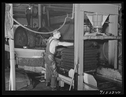 Bags full of crushed olives are put into hydraulic press for oil extraction. Lindsay, California