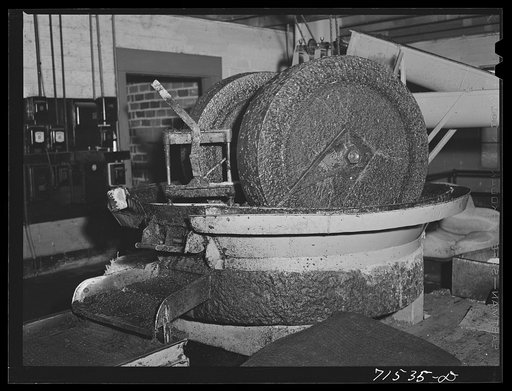 A granite millstone crushes the olives which have first been washed and warmed. This is the first step in making olive oil. Lindsay, California