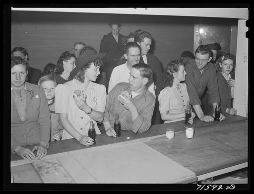 Woodville, California. FSA (Farm Security Administration) farm workers' community. Migrant agricultural workers eating hamburgers at the Saturday night dance