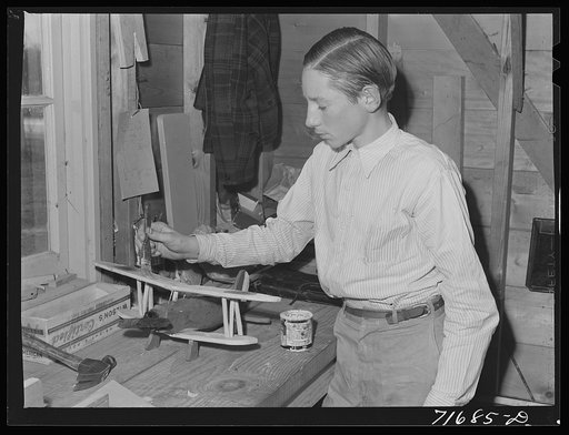 Tulare County, California. FSA (Farm Security Administration) farm workers' camp. Son of an agricultural worker making a model plane in the workshop