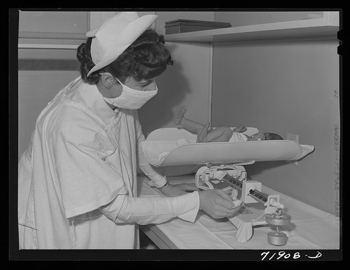 Nurse weighs baby in the nursery of the Cairns General Hospital at the FSA (Farm Security Administration) farm workers' community. Eleven Mile Corner, Arizona