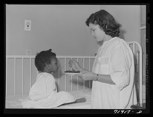 Untitled photo, possibly related to: NYA (National Youth Association) girl feeds lunch to little girl who is a patient at the Cairns General Hospital located at the FSA (Farm Security Administration) farm workers' community at Eleven Mile Corner, Arizona