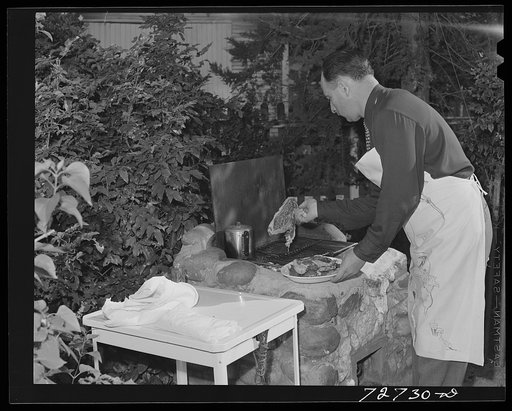 Turlock, California. Man of the house barbecues steaks over open grill in his backyard. This family keeps vegetables, fruits and meats in frozen food lockers in town