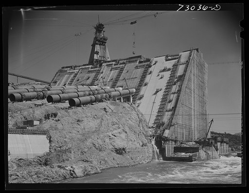 Shasta Dam, Shasta County, California. One side of Shasta Dam under construction, with the Sacramento River still flowing through the opening between the two sides of the dam. Water will flow through the penstocks to the hydroelectric plant