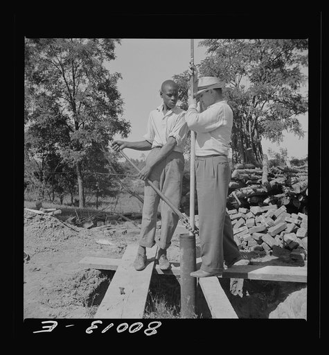Mr. Slater, well engineer, and helper, settle drop pipe into casing. John Fredrick well Project, Saint Mary's County, Maryland