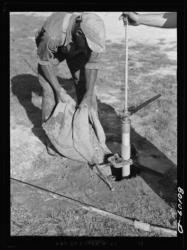 Placing small gravel in bore hole around well point. Safe well demonstration, Ridge, Maryland, Saint Mary's County