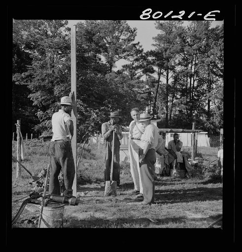 Untitled photo, possibly related to: Tamping in earth around top of pump after fill of gravel has been poured around the casing. Ridge well project, Saint Mary's County, Maryland