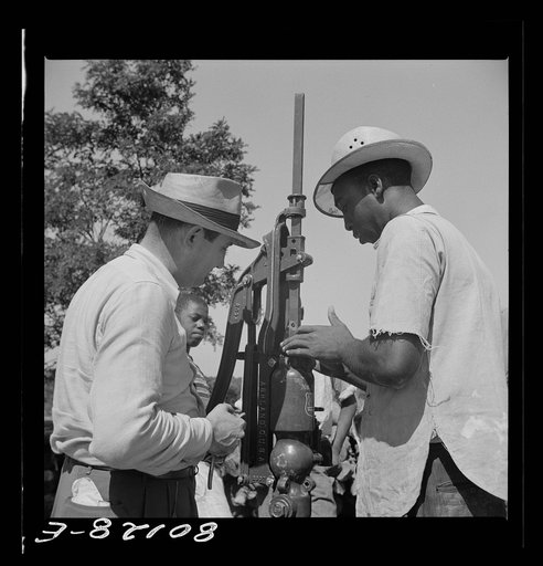 Well worker adjusts washer around pump under supervision of Mr. Slater, engineer. Ridge well project, Saint Mary's County, Maryland