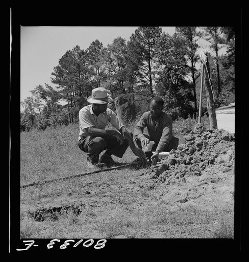 Well workers feel the contents of drill to determine how deep they will have to dig--they must drill through mud and clay till they strike sand or gravel. Ridge well project, Saint Mary's County, Maryland