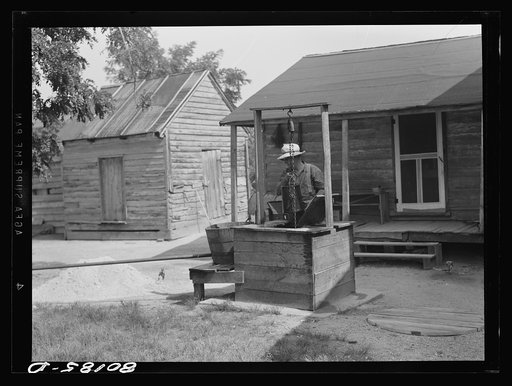 Mr. John Hardesty draws himself a bucket of water from old well before repairs. John Hardesty well project, Charles County, Maryland