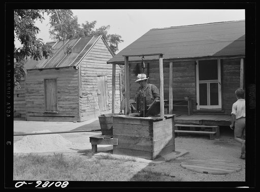 Untitled photo, possibly related to: Mr. John Hardesty draws himself a bucket of water from old well before repairs. John Hardesty well project, Charles County, Maryland