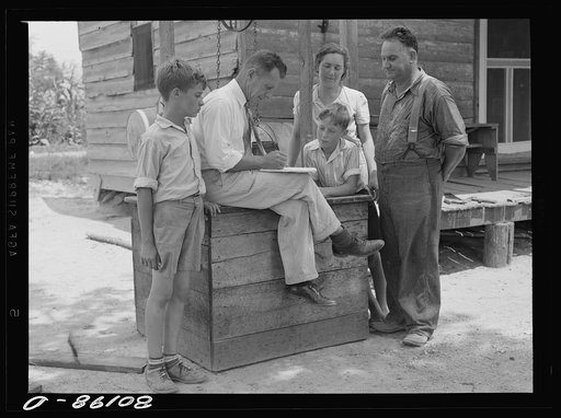 County supervisor talking over home plan with the Hardesty family resting on removed well top. Charles County, Maryland