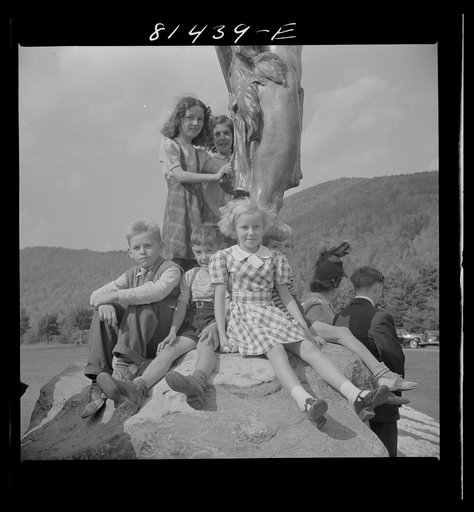 Children crowded up on the feet of "Hail to the Sunrise" bronze Indian to have their pictures taken. Mohawk Trail, Massachusetts