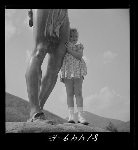 A little girl clinging to the bronze statue of an Indian on the Mohawk Trail in Massachusetts