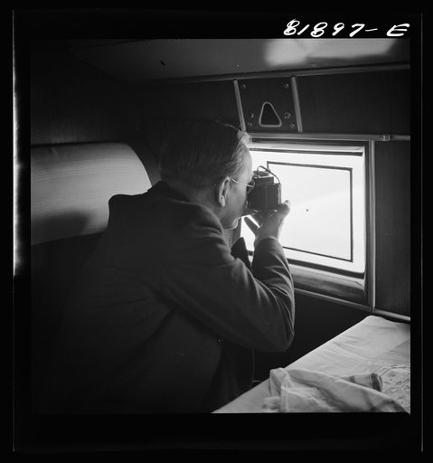 Passenger taking pictures with a dollar camera from the window of an American airliner