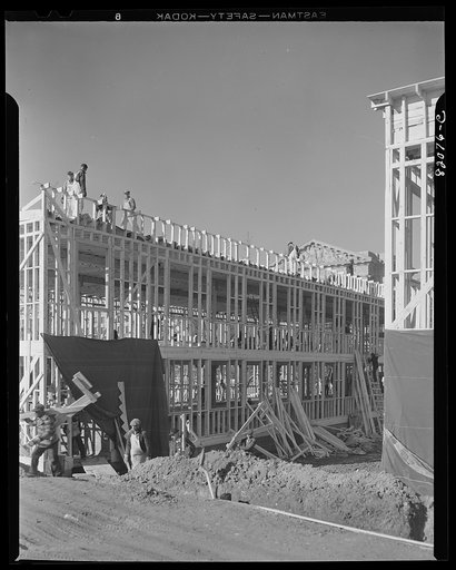 Nailing up asbestos rock wall board on emergency defense office space construction project. Washington, D.C.