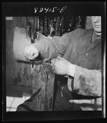 Honey Brook, Pennsylvania (vicinity). Amish farmhand mending harness on the Zook farm