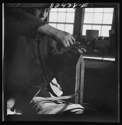 Untitled photo, possibly related to: Honey Brook, Pennsylvania (vicinity). Amish farmhand mending harness on the Zook farm