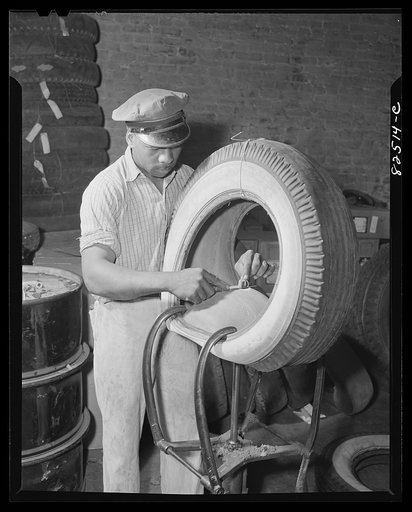 Washington, D.C. Washington tire shop. Cutting tread away from a hole to be vulcanized
