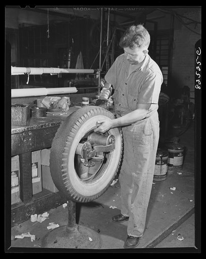 Washington, D.C. Washington tire store. Brushing on rubber cement to make recap secure before vulcanizing