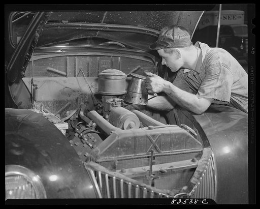 Washington, D.C. Mechanic refilling a car with oil after draining the crankcase