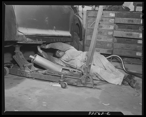 Untitled photo, possibly related to: Arlington, Virginia. Auto refinishing plant. Installing a new muffler