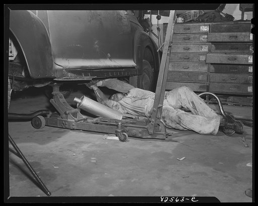 Untitled photo, possibly related to: Arlington, Virginia. Auto refinishing plant. Installing a new muffler