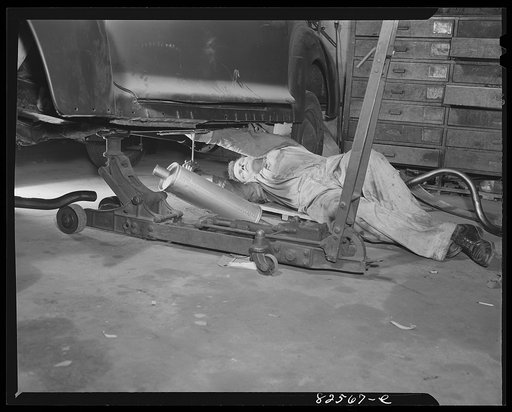 Untitled photo, possibly related to: Arlington, Virginia. Auto refinishing plant. Installing a new muffler