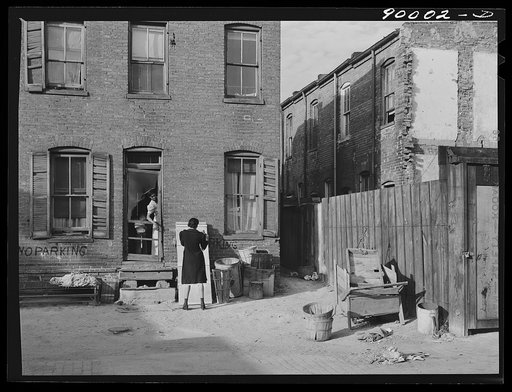 Negro slums. Alexander Court between K and L streets, N.W. Woman and her two children have lived in four small rooms eight and one half years and pay twelve fifty a month for rent. Water and privy in the yard. Rents in nearby houses have gone up but not here. Washington, D.C.