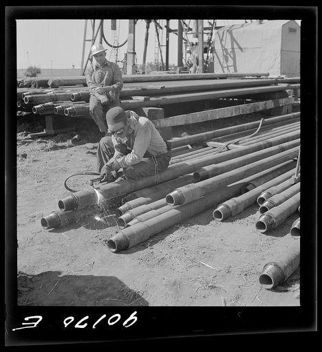 Untitled photo, possibly related to: Floyd Swick, welder from Newton, Kansas worked in oil fields about ten years; cutting tool joints off a drill pipe in Goodrich field of Continental oil company. Valley Center oil field near Wichita, Kansas