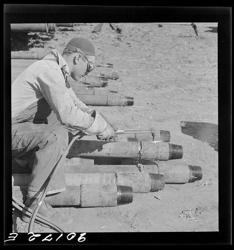 Untitled photo, possibly related to: Floyd Swick, welder from Newton, Kansas worked in oil fields about ten years; cutting tool joints off a drill pipe in Goodrich field of Continental oil company. Valley Center oil field near Wichita, Kansas