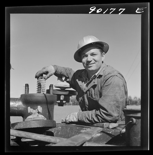 Untitled photo, possibly related to: Elmer Womack, derrick man from Fairfax, Oklahoma overhauling mud hog where oil well is being drilled in Goodrich field of Continental oil company. Valley Center oil field near Wichita, Kansas. He has been working in Kansas fields about six years, used to be a pum
