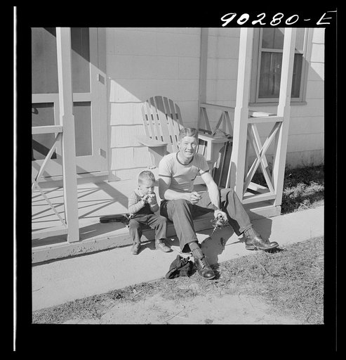 Untitled photo, possibly related to: Radford, Virginia. Sunset Village, FSA housing project. Fred B. Williams from Savannah, Georgia, and his son "Buddy" cleaning the car distributer on the porch of his home. 803 9th Street