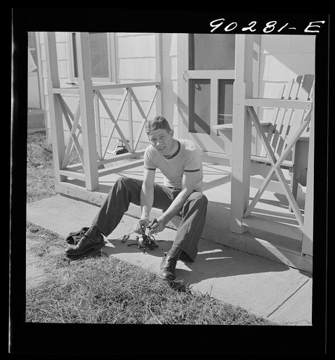 Untitled photo, possibly related to: Radford, Virginia. Sunset Village, FSA housing project. Fred B. Williams from Savannah, Georgia, and his son "Buddy" cleaning the car distributer on the porch of his home. 803 9th Street