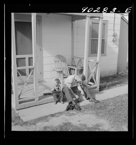 Untitled photo, possibly related to: Radford, Virginia. Sunset Village, FSA housing project. Fred B. Williams from Savannah, Georgia, and his son "Buddy" cleaning the car distributer on the porch of his home. 803 9th Street