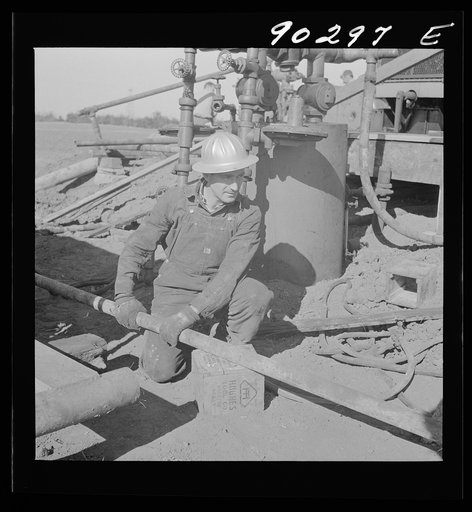 L.N. McCullough, from Arkansas, breaking out gas line, by oil well being drilled in Goodrich field of Continental oil company near Wichita, Kansas