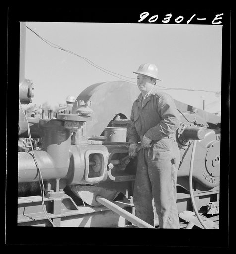 Elmer Womack, derrick man from Fairfax, Oklahoma, overhauling mud hog where oil well is being drilled in Goodrich field of Continental oil company. Valley Center oil field near Witchita, Kansas. He has been working in Kansas fields about six years, used to be a pumper and worked in oil fields since 
