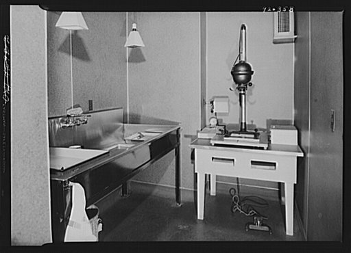 U.S. FSA (Farm Security Administration), later U.S. Office of War Information, photograph laboratory in the Auditor's Building. Washington, D.C. Individual printing room, showing a Leitz miniature enlarger
