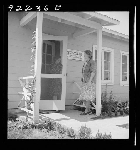 Untitled photo, possibly related to: Tulare County, Farmersville, California. Farm Security Administration (FSA) camp for migratory agricultural workers. Entering clinic of Agricultural Workers' Health and Medical Association (FSA) for nurse's help with sick baby. Older woman says, "I'm just a neigh