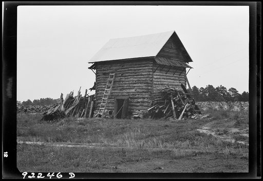 Untitled photo, possibly related to: Tobacco barn without front shelter. The footpath across the field leads to the main house. Person County, North Carolina