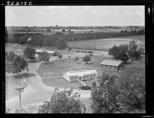Untitled photo, possibly related to: Entrance to camp showing clinic (light building in foreground). Same as 19635. Farmersville, California