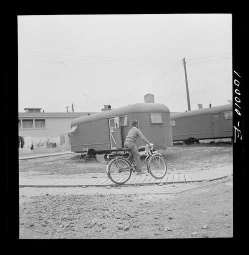 Arlington, Virginia. FSA (Farm Security Administration) trailer camp project for Negroes. Young occupant gets around by bicycle. The community building is in the background