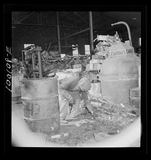 Washington, D.C. Scrap salvage campaign, Victory Program. Picking up iron scraps from floor with a magnet in warehouse of a wholesale junk company
