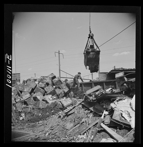 Untitled photo, possibly related to: Washington, D.C. Scrap salvage campaign, Victory Program. Crane loads blocks of scrap metal onto a freight car in yard of wholesale junk company