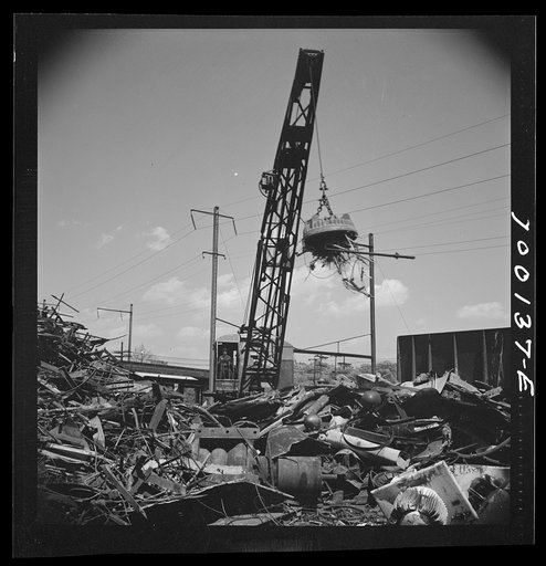 Untitled photo, possibly related to: Washington, D.C. Scrap salvage campaign, Victory Program. Electro-magnet loads metal scrap onto freight car in wholesale junkyard