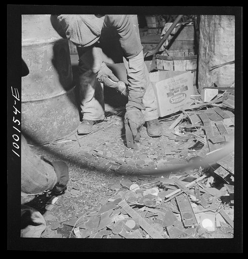 Washington, D.C. Scrap salvage campaign, Victory Program. Picking up pieces of iron scrap from the floor with a magnet in wholesale junk dealer's warehouse