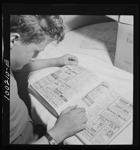 Washington, D.C. Scrap salvage campaign, Victory Program. This boy is looking up junk dealers in the telephone directory. He wants a junk dealer to pick up the scrap which he has collected and stored in his cellar