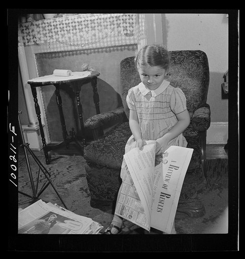 Untitled photo, possibly related to: Washington, D.C. Scrap salvage campaign, Victory Program. This little girl folds the Sunday paper to take to school for contribution in the scrap collecting campaign