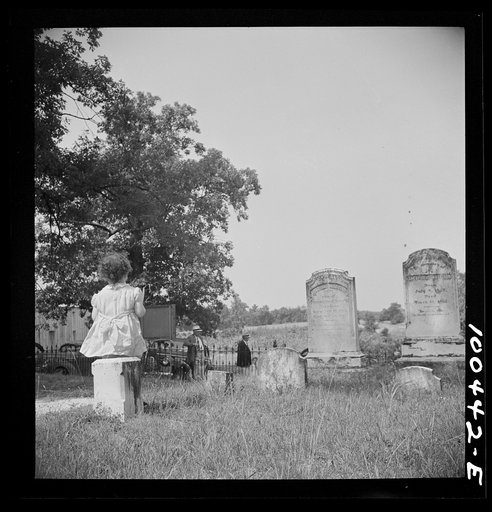 St. Mary's County, Maryland. Minister's daughter sitting on a tombstone, watching people come to All Faith Church where her father is minister
