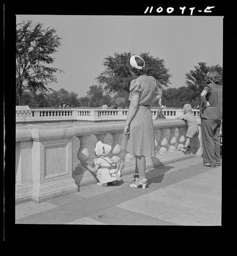 Detroit, Michigan. Woman adjusting a harness strap to prevent child from getting lost in zoological park